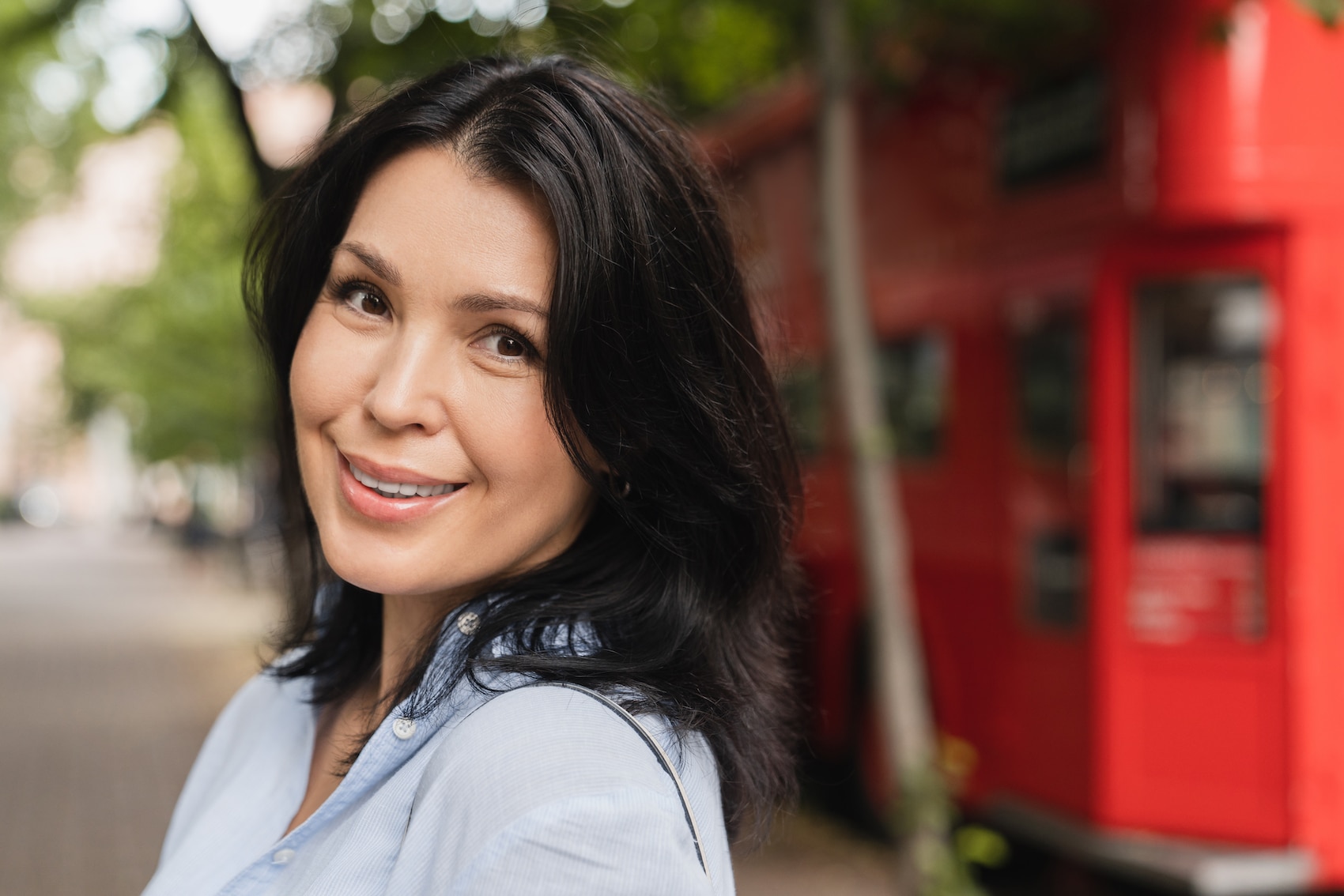Smiling confident middle-aged caucasian woman with dark brown hair looking at the camera