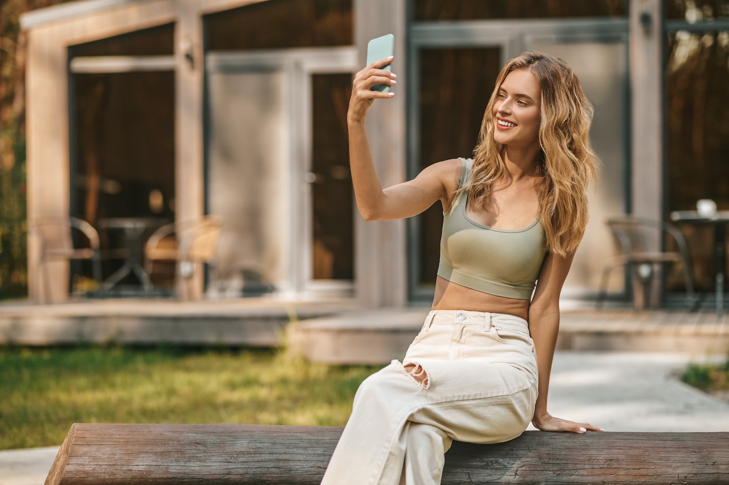 Smiling woman looking at smartphone in outstretched hand