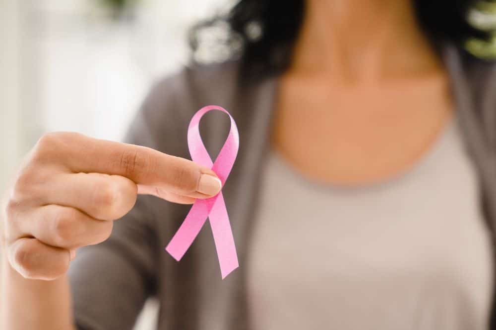 woman holding pink ribbon representing fight against cancer as part of addressing sex and cance
