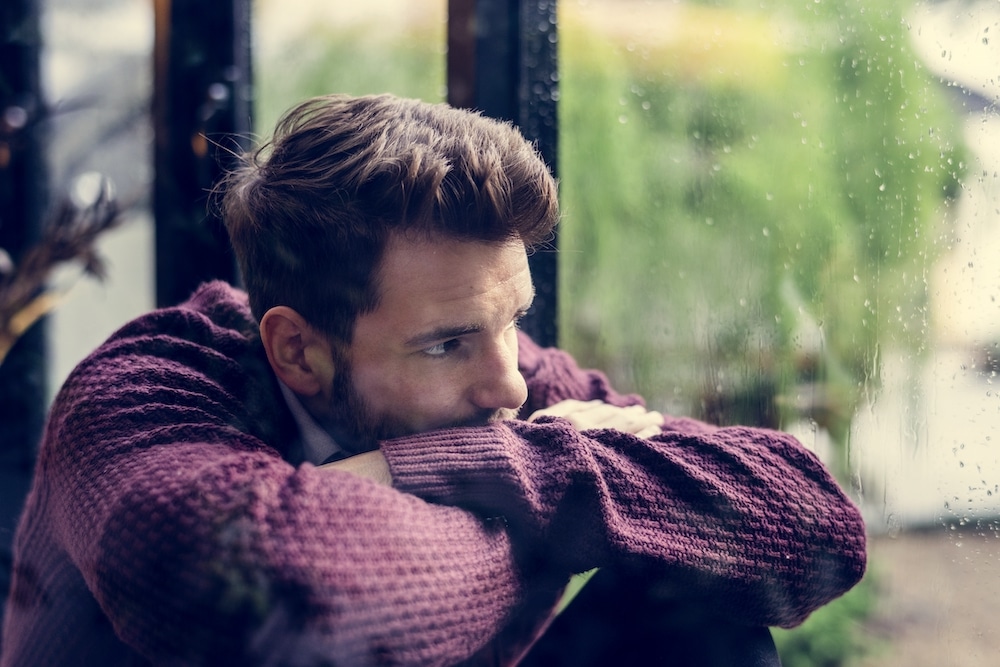 Young man looking outside the window while sitting
